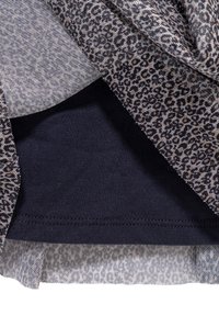 Warstwa odzieży z tkaniny w jasnoszary wzór w panterkę na czarnym tle, o gładkiej fakturze. Doł jest lekko zaokrąglony.