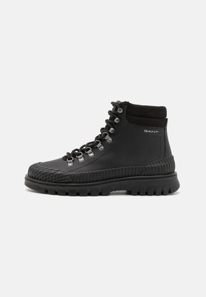 Black hiking boots with a smooth leather upper, rubber accent on the toe, metallic eyelets, and a rugged textured sole. Brand logo on the side.