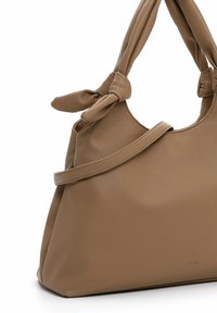 Leather handbag in a muted tan color with knotted handle accents, a structured shape, and a grainy texture. Features a side strap.