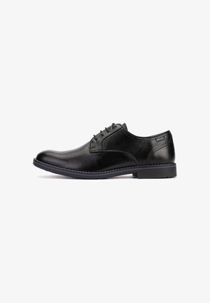 Chaussure habillée pour homme en cuir noir avec fermeture à lacets et petit talon, vue de profil sur fond blanc.
