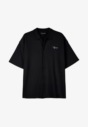 Must värvusega lühikeste varrukatega nööbiga särk, valmistatud tekstuurriidest, millel on mugav lõige ja väike valge logo vasakul küljel.