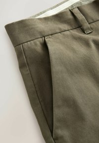 Olivengrønne plisserede bukser lavet af et tekstureret stof, med flad front og standard talje med bæltestrop.