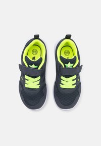 Baskets de sport bleu marine foncé avec tige en maille, lacets jaunes, sangle Velcro et semelles en caoutchouc blanches. Comprend des indications de taille sur les semelles intérieures.