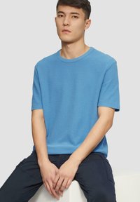 Blauwe t-shirt met korte mouwen, gemaakt van katoen, met een ronde hals, een gladde textuur en een relaxte pasvorm, gedragen met donkere broeken.