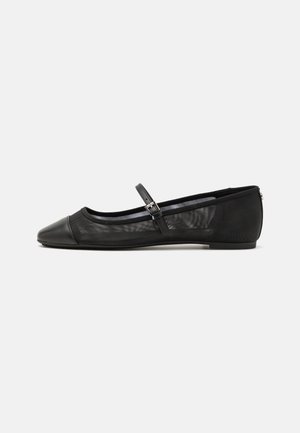 Ballerines noires avec un corps en maille texturée, bout rond, et une fine sangle à la cheville avec un détail de boucle métallique. Semelle plate.