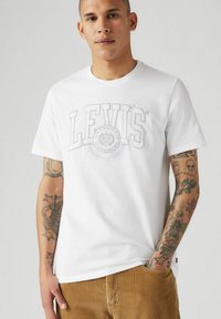 Vit bomull t-shirt med en stor grå Levi's logotyp över bröstet. Korta ärmar, rund hals och en avslappnad passform.