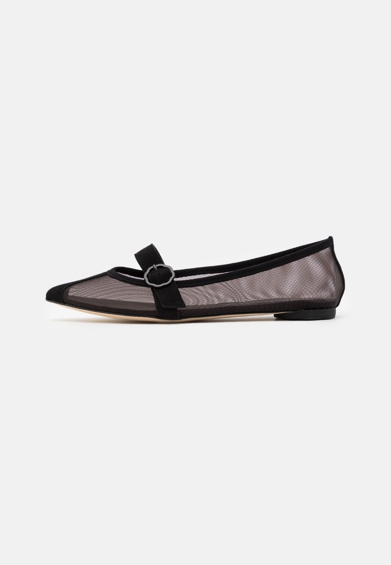 Chaussure plate noire à bout pointu avec côtés en mesh et une lanière noire avec boucle circulaire sur le dessus.