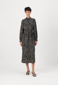 Black long-sleeve dress with a paisley pattern in cream. Features a collared neckline and a tie belt at the waist. Smooth texture.