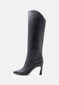 Bottes hautes en cuir noir jusqu'au genou avec un bout pointu et un talon fin. Texture lisse et design minimaliste, avec une tige haute sans ornements.