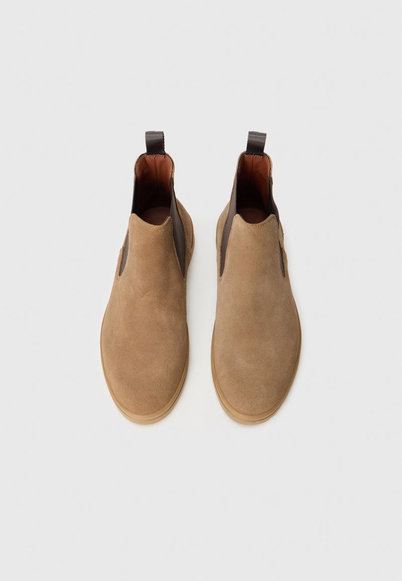 Stivaletti in suede marrone con pannelli elastici laterali e suola in gomma liscia. Punta tonda e linguetta sul tallone per indossarli facilmente.