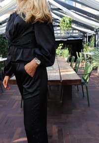 Melns satīna divdaļīgs komplekts ar sasienamu topu ar pūkainām piedurknēm un biksēm ar smalkām rhinestone rotājumu detaļām.