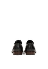 Pantofi din piele neagră cu un finisaj uniform, vârf rotunjit și toc mic din lemn maro, având detalii minime și un design fluid.