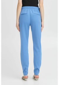 Pantalones de color azul claro con corte relajado, cinturilla elástica, bolsillos laterales y dos bolsillos traseros. Tejido suave de un solo color, sin patrones.