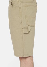 Beige cargo shorts yang terbuat dari kain campuran katun dengan saku samping dan detail jahitan. Memiliki potongan lurus dan desain panjang sampai lutut.