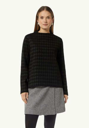 Black houndstooth-patterned long-sleeve top with a crew neckline, paired with a gray herringbone skirt. Smooth texture, relaxed fit.