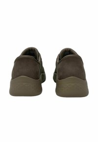 Zapatillas deportivas marrones con un acabado de ante suave, tacón redondeado y suela de goma texturizada. Presenta un diseño minimalista sin marcas visibles.