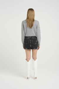 Grijze gebreide trui, zwarte denim minirok met rafelige zoom en witte hoge hakken met puntige toppen. Schoon, minimalistisch ontwerp.