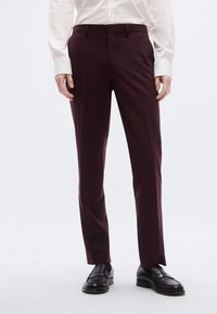 Μπορντό παντελόνια σε γραμμή tailored από λείο ύφασμα, με ίσια μπροστινή όψη, θηλιές για ζώνη και στενούς ποδόγυρους, συνδυασμένα με μαύρα δερμάτινα loafers.