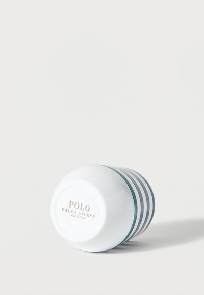 Hvit keramikk-kopp med marineblå horisontale striper liggende på siden, med teksten "Polo Ralph Lauren Made in China" på bunnen.