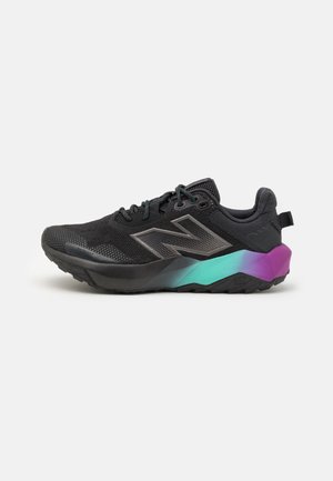 Zapatilla deportiva negra con parte superior de malla, diseño con cordones y suela degradada que pasa de verde azulado a morado sobre un fondo blanco.