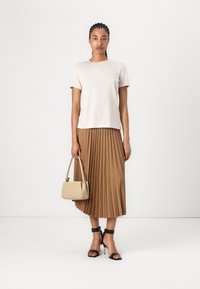 Beige t-shirt with logo, pleated brown midi skirt, black heeled sandals, and a small beige handbag. Smooth fabric and sleek design.