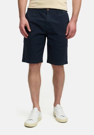 Navy blue cotton shorts with a regular fit, button closure, and pockets. Paired with white sneakers featuring a textured design.