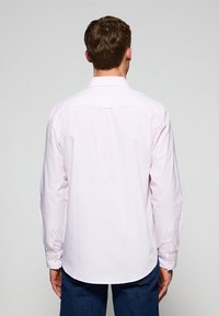 Lichtroze gestreepte overhemd met lange mouwen, rugpaspel-detail en knopenmanchetten, gecombineerd met donkerblauwe denim jeans.