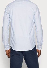 Jasnoniebieska koszula w paski na guziki, z długimi rękawami, dopasowanym krojem, zaokrąglonym dołem i mankietami na guziki. Gładki bawełniany materiał.