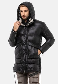 Schwarze Steppjacke mit Kapuze, Reißverschluss vorne und horizontalen Nähten. Verfügt über ein Logo auf der Brust und Taschen. Glattes, glänzendes Material.