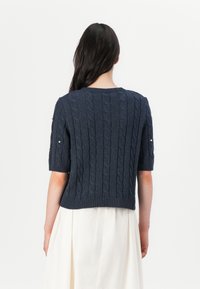 Navy blue knitted sweater with short sleeves, featuring a cable pattern and ribbed hem. Has decorative pearl accents on the sleeves.