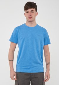 T-shirt blu a girocollo, maniche corte, realizzato in morbido tessuto misto cotone con una leggera trama. Piccolo logo stampato sul petto.
