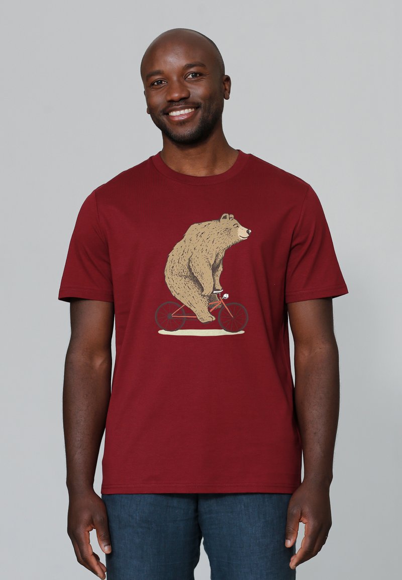 T-shirt à manches courtes maroon avec un graphisme d'un ours faisant du vélo rouge. Tissu doux avec un col rond et une coupe décontractée.