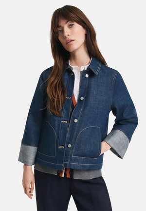 Mørkeblå denimjakke med knapper, to frontlommer og oppbrettede denimmansjetter. Har kontrastsømmer og en avslappet passform.