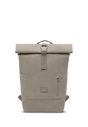 Mochila de color gris claro con cierre enrollable, bolsillo frontal con cremallera, hebilla central y parche con el logo "Johnny Urban".