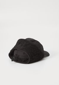 Crni šešir s mekanim, plišanim oblogom i ravnim vizirjem. Vanjska strana ima glatku, mat teksturu i uključuje podešavanje s povlačenjem.