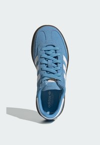 Modré semišové tenisky s bílým designem tří pruhů, zaoblenou špičkou, šněrováním a hnědou gumovou podrážkou. Texturovaný svršek s logem.