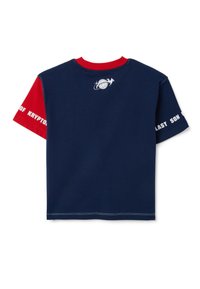 Camiseta azul marino con mangas cortas rojas, que presenta un gráfico blanco de un globo y el texto "ÚLTIMO HIJO DE KRYPTON" en la manga. Tejido de algodón.