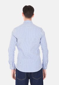 Camicia a maniche lunghe blu e bianca a righe con polsini a bottone, colletto alla francese e orlo dritto, realizzata in cotone leggero.