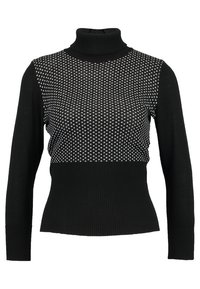 Pull à col roulé noir avec un bas en côtes texturées. La partie supérieure présente un motif avec des pois blancs sur un fond noir.