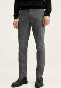 Grijze geruite broek met een slim fit, gemaakt van een gestructureerde stof en een subtiel ruitpatroon, gecombineerd met zwarte enkellaarsjes.