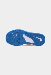 Blaue und weiße Sportschuhsohle mit strukturiertem Profil und Nike-Swoosh-Logo auf hellem, einfarbigem Hintergrund.