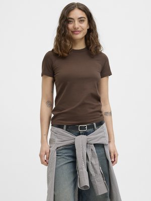 Braunes T-Shirt mit kurzen Ärmeln und Rundhalsausschnitt, kombiniert mit hellblauen Jeans und einem grau gestreiften Hemd, das um die Taille gebunden ist. Glatte Stofftextur.