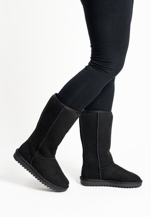 Schwarze kniehohe Stiefel aus Wildleder mit strukturierter Oberseite, Gummisohle und sichtbaren Nähten. Verfügen über eine flache Sohle und ein klassisches Design.