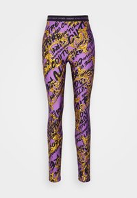 Lila leggings med ett utsmyckat guldmönster, svart text och en svart midja med "Versace Jeans Couture"-logotyp.