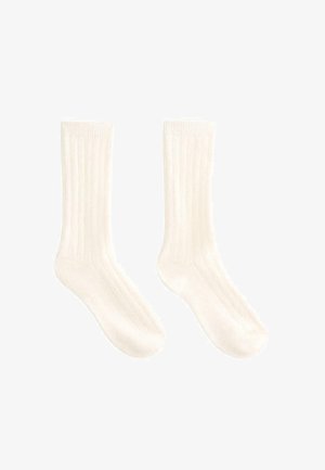 Weiße gerippte Socken aus weichem Material, mit vertikalen Streifen und einem bequemen Bündchen. Die Länge reicht bis zur Mitte der Wade.