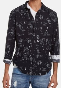 Camisa negra abotonada con gráficos impresos en blanco de tacos y otros diseños. Mangas largas con puños enrollados, tela suave.