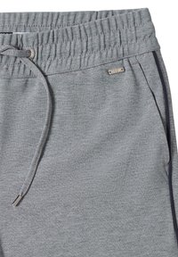 Pantalons à taille élastique grise avec cordon de serrage, poches latérales, bande latérale noire, et petite étiquette en métal de la marque au-dessus de la poche droite.