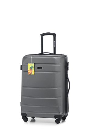 Gray hard-shell suitcase with textured surface, retractable handle, dual spinner wheels, and brand tag featuring a pineapple design.