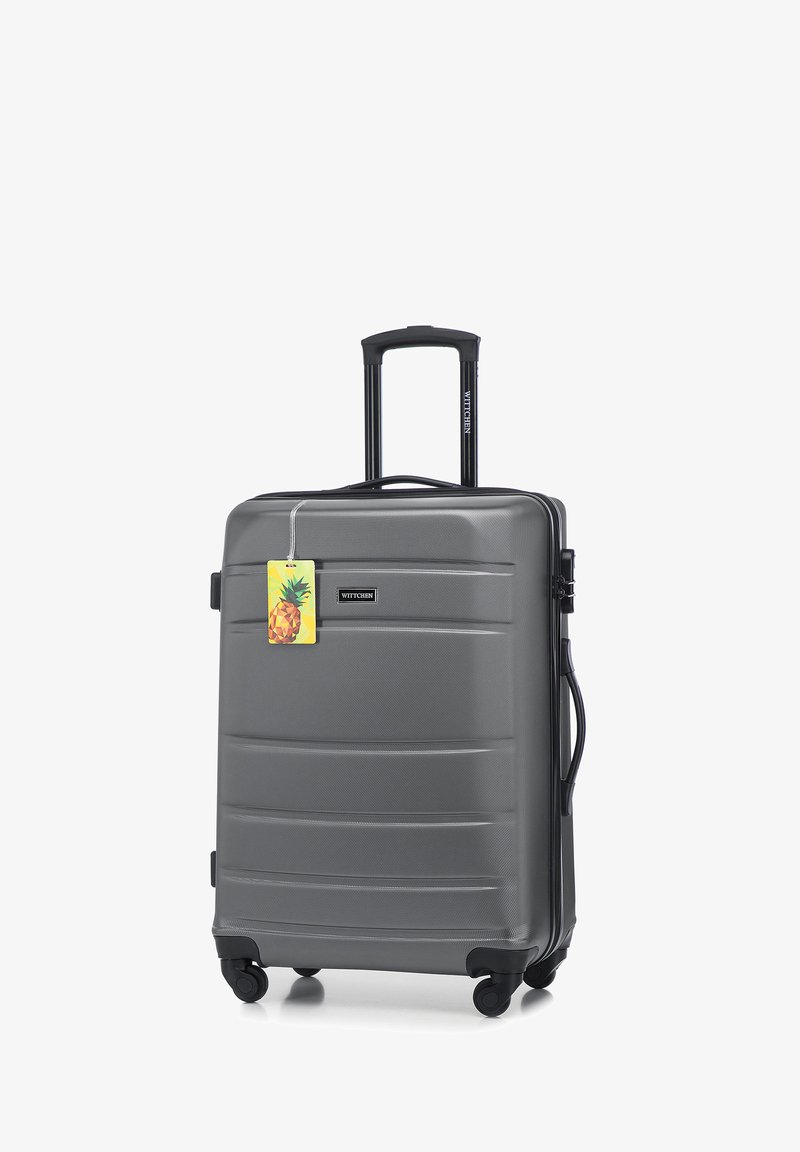 Grijze harde koffer met gestructureerd oppervlak, uitschuifbare handgreep, dubbele spinnerwielen en een merkaartje met een ananasontwerp.