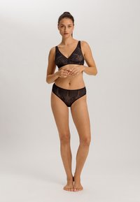 Set di lingerie nera composto da un bralette con design a scollo a V e coordinati slip a vita alta, entrambi realizzati in un tessuto trasparente e testurizzato.